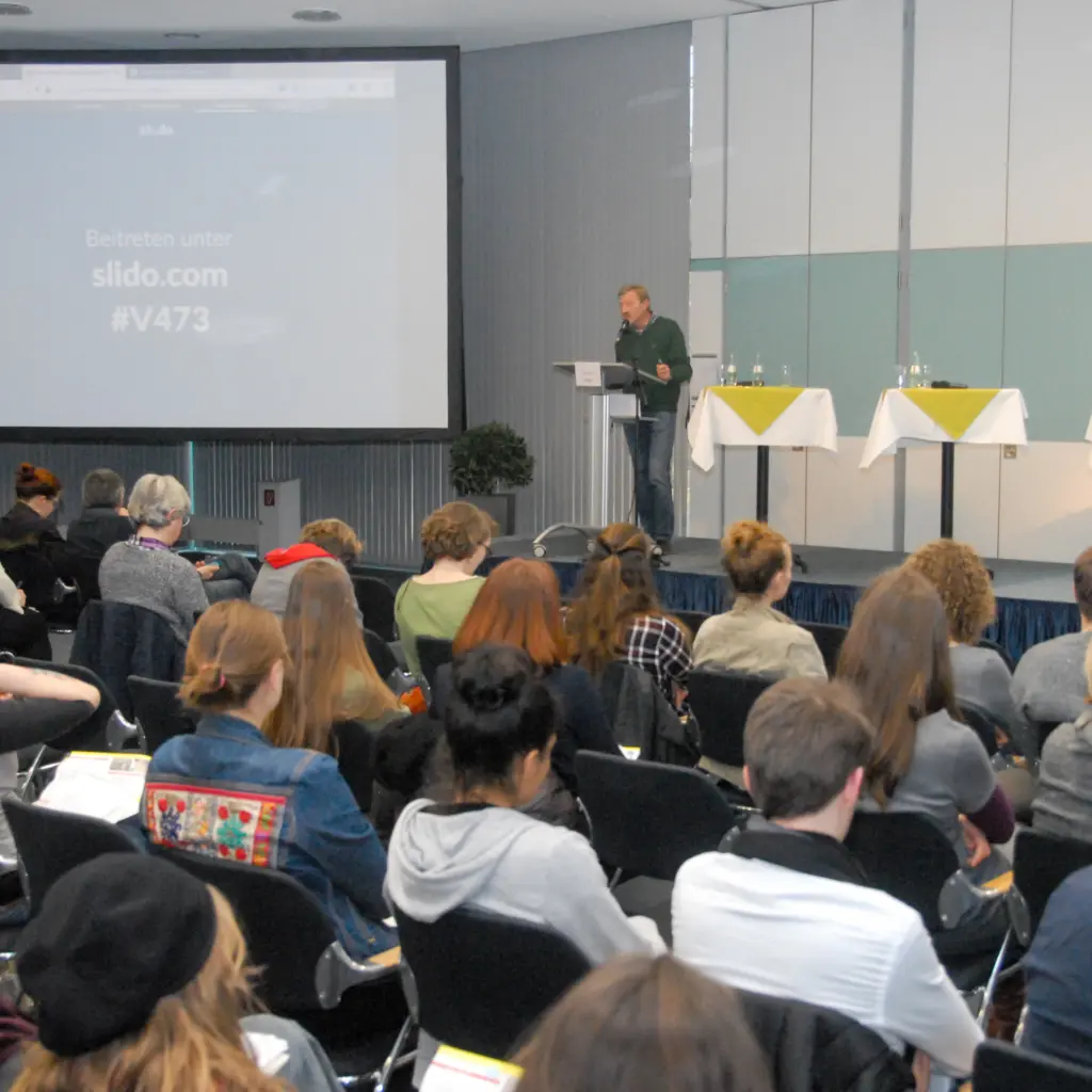 Ulrich Post hält Vortrag am Rednerpult in Plenum // Bild: Erik-Holm Langhof