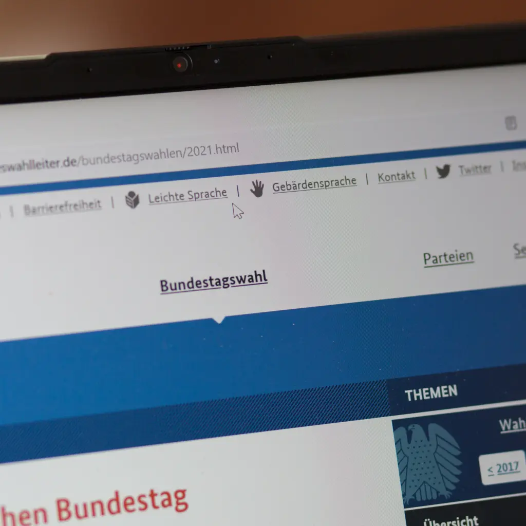 Ein Laptopbildschirm auf welchem die Seite des Bundeswahlleiters zu sehen ist. Der Mauszeiger liegt auf den Links zu Barrierfreier Bedienung.