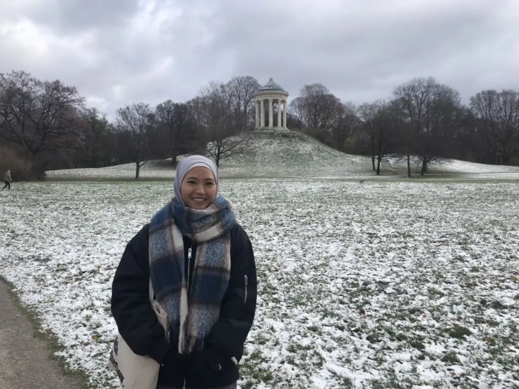 Zohra steht lächend im Englischen Garten in München, Deutschland.